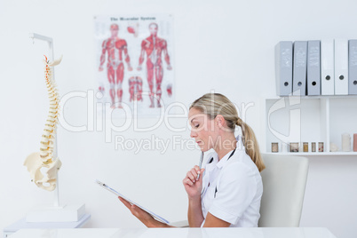 Doctor writing on clipboard at her desk