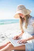 Woman using laptop and wearing hat