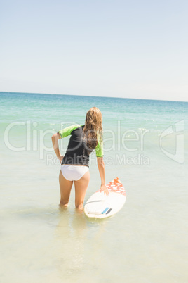 Wear view of pretty blonde preparing to surf