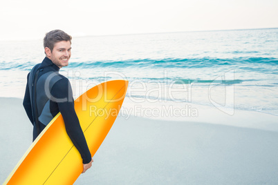 Man in wetsuit with a surfboard on a sunny day