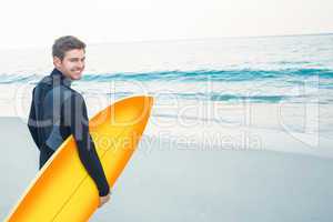 Man in wetsuit with a surfboard on a sunny day