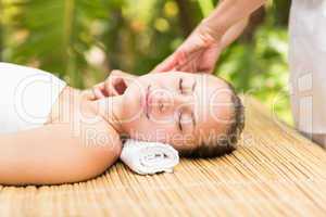 Attractive young woman receiving facial massage at spa center
