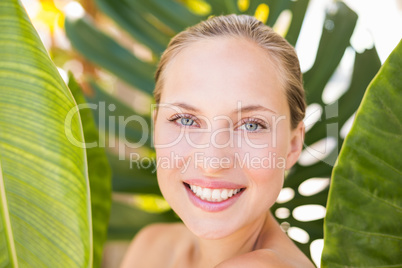 Beautiful blonde smiling at camera behind leaf