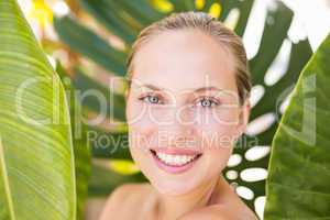 Beautiful blonde smiling at camera behind leaf