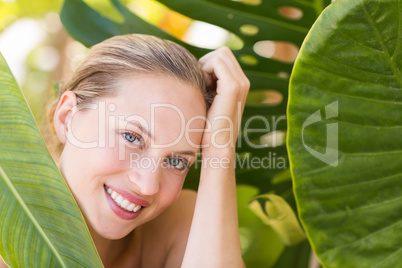 Beautiful blonde smiling at camera behind leaf