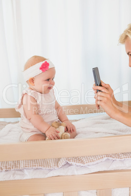 Happy mother taking a picture of her baby girl
