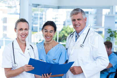 Team of doctors working on their files and smiling at camera