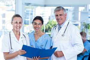 Team of doctors working on their files and smiling at camera