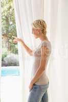 Smiling blonde woman look outside and showing