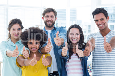 Creative business people gesturing thumbs up by blackboard