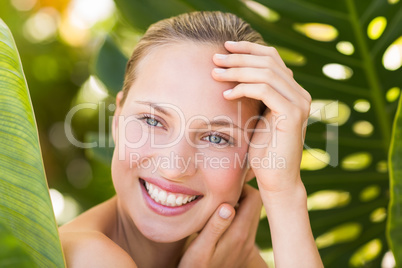 Beautiful blonde smiling at camera behind leaf