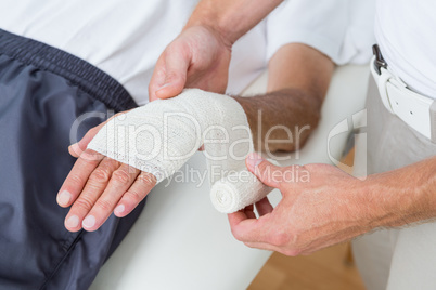 Doctor bandaging his patient hand