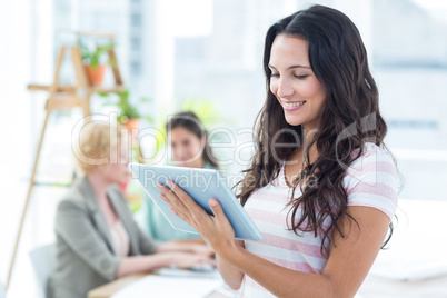 Smiling businesswoman using a tablet with colleagues