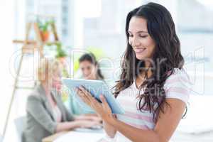 Smiling businesswoman using a tablet with colleagues