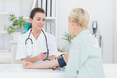 Doctor taking blood pressure of her patient