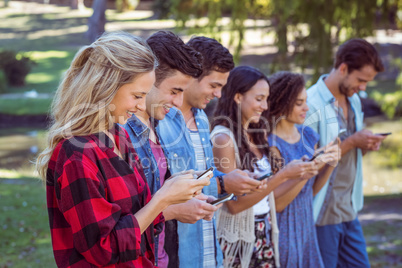 Happy friends in the park using their phones