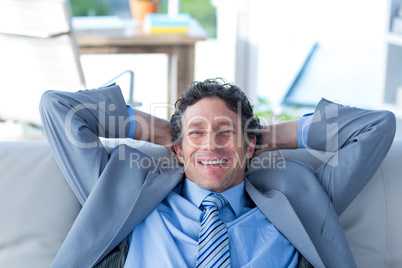 Businessman smiling at camera sitting on couch