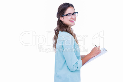 Pretty geeky hipster writing on notebook and smiling at camera