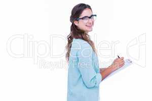 Pretty geeky hipster writing on notebook and smiling at camera