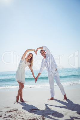 Happy couple forming heart shape with their hands