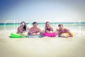 Happy friends lying on inflatable mattress above the water