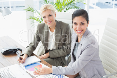 Smiling businesswomen looking at camera and working together