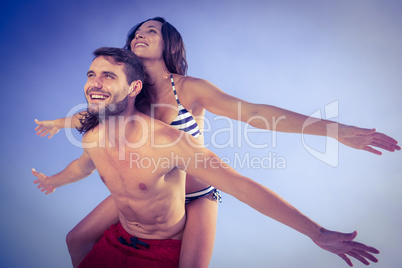 Man giving piggy back to his girlfriend at the beach