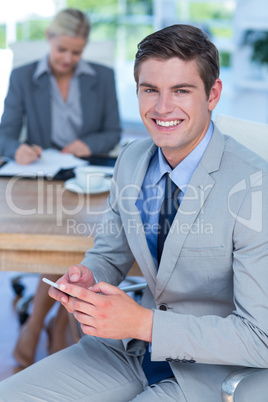 Smiling businessman texting on his mobile phone