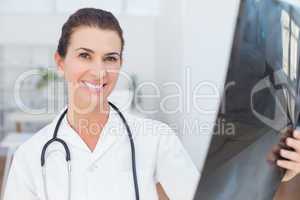 Smiling doctor looking at camera with Xray