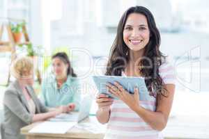 Smiling businesswoman using a tablet with colleagues