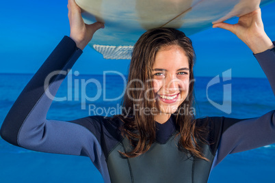 Woman in wetsuit with a surfboard on a sunny day