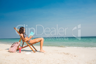 Pretty brunette reading a book on deck chair