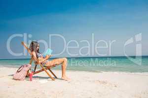 Pretty brunette reading a book on deck chair