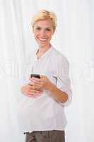 Portrait smiling blonde pregnant using her mobile
