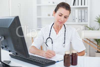 Smiling doctor writing on clipboard