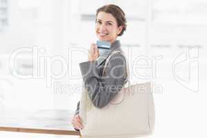 Smiling businesswoman looking at camera and holding credit card