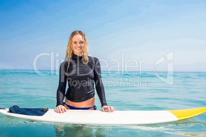 Woman with a surfboard smiling at camera