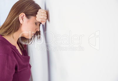 Depressed woman leaning her head against a wall