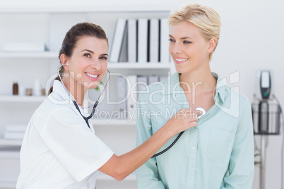 Doctor listening to patients chest with stethoscope