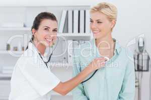 Doctor listening to patients chest with stethoscope