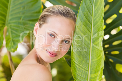 Beautiful blonde smiling at camera behind leaf