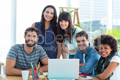 Happy creative business team gathered around a laptop