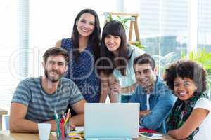 Happy creative business team gathered around a laptop
