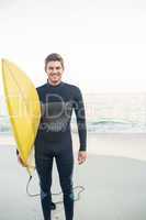 Man in wetsuit with a surfboard on a sunny day