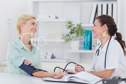 Doctor taking blood pressure of her smiling patient