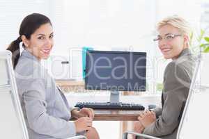 Smiling businesswomen looking at camera and working together