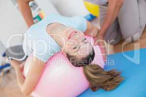 Trainer working with woman on exercise ball