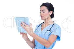 Young nurse in blue tunic using a laptop