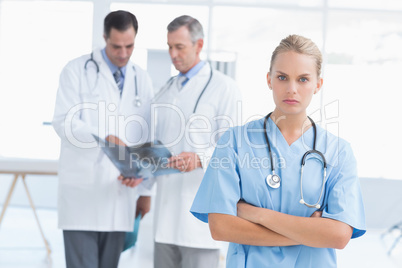 Irritated doctor looking at camera while her colleagues works