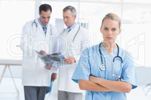 Irritated doctor looking at camera while her colleagues works